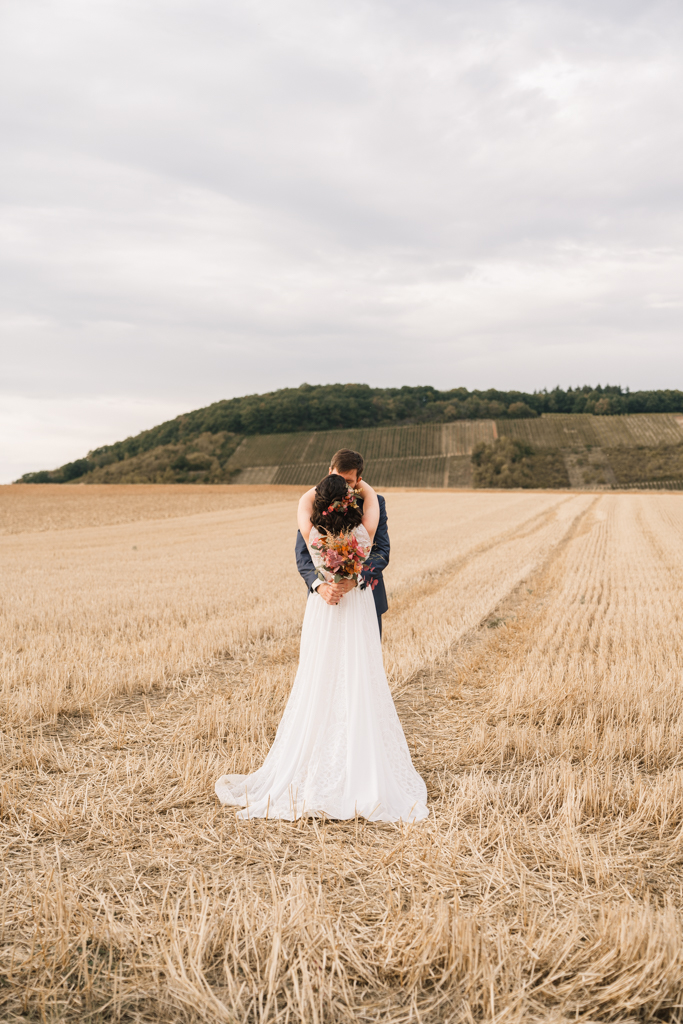 Brautstrauß vor dem Rücken der Braut auf einem Stroh Feld.