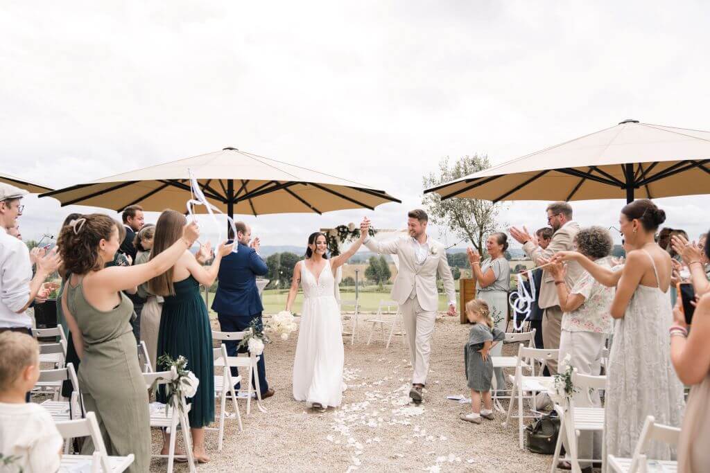 Hochzeitsfotograf fängt jubelndes Brautpaar beim Auslaufen nach der Trauung in einer Hochzeitsreportage ein.